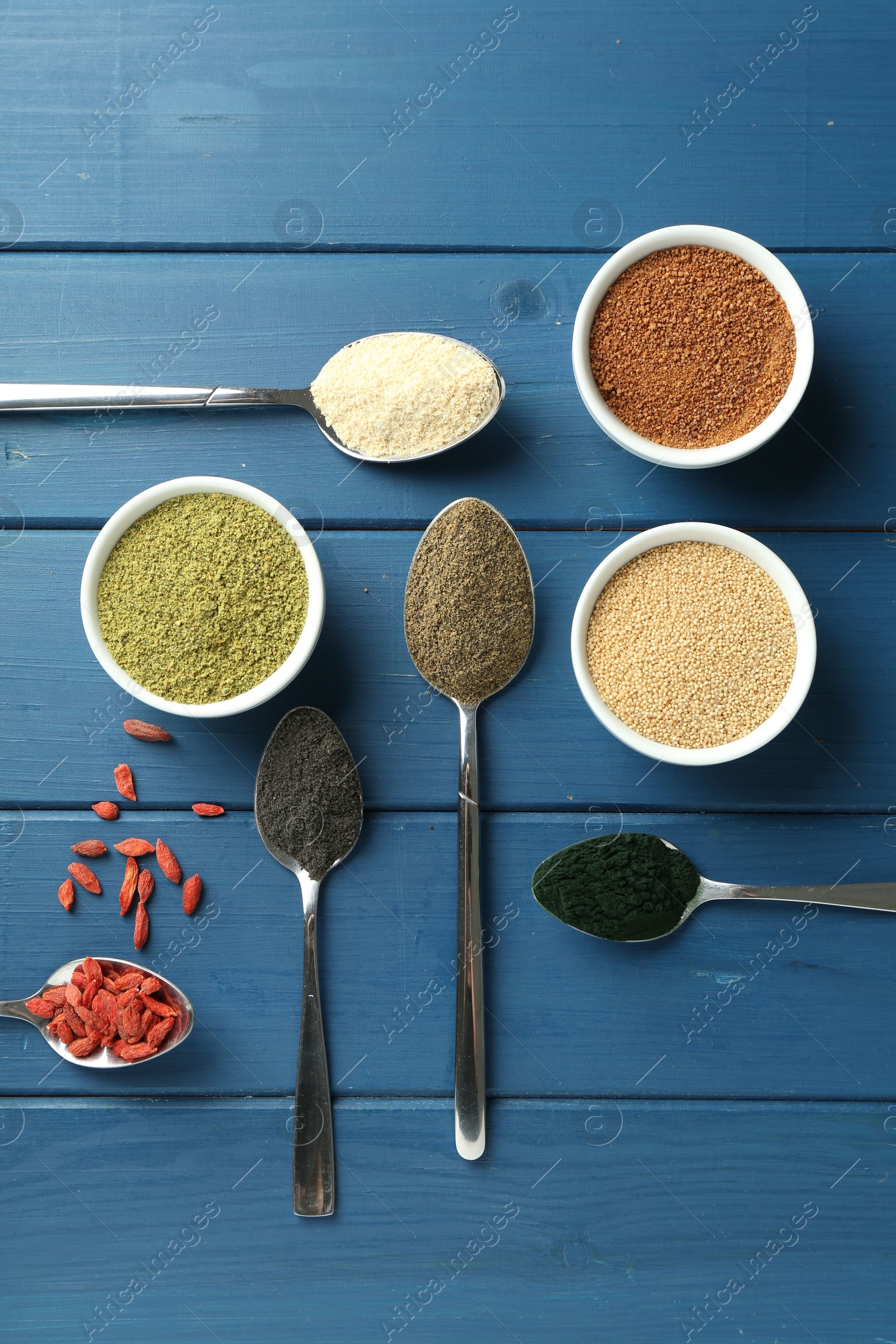 Photo of Different superfood powders on blue wooden table, flat lay