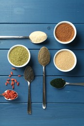 Different superfood powders on blue wooden table, flat lay