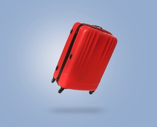 Image of Red suitcase in air on light blue background