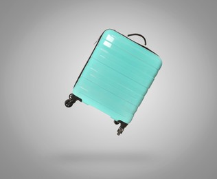 Image of Turquoise suitcase in air on light grey background