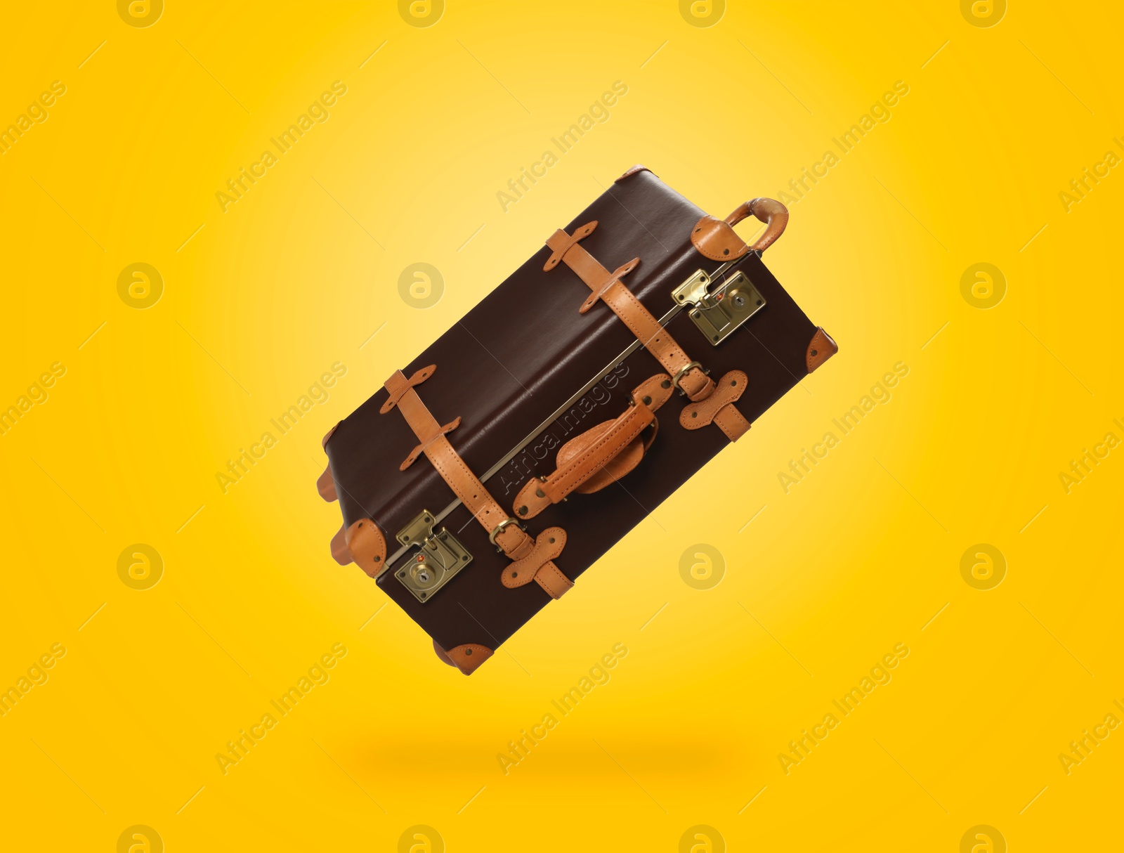 Image of Vintage suitcase in air on yellow background