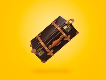 Image of Vintage suitcase in air on yellow background