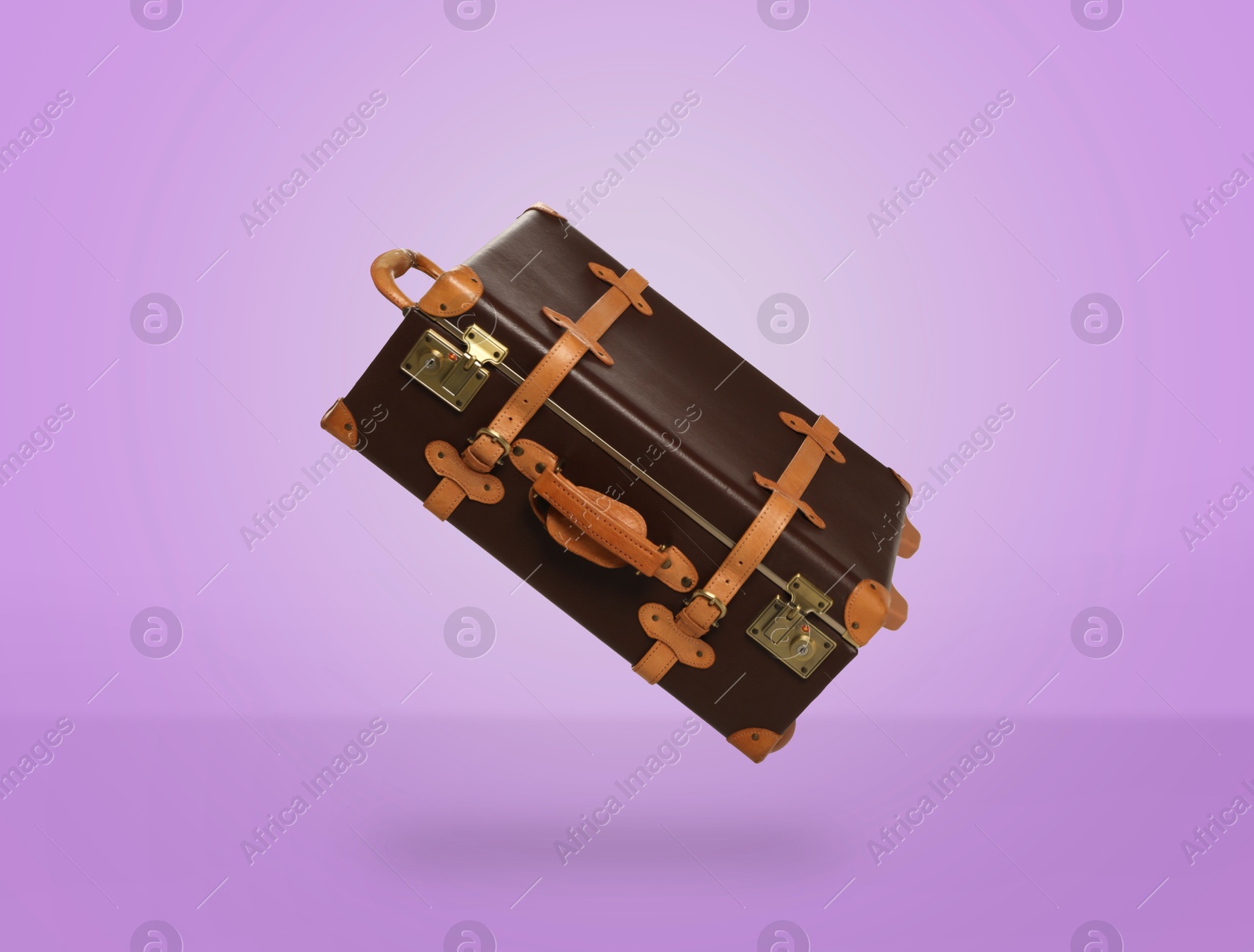 Image of Vintage suitcase in air on violet background