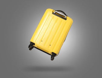 Image of Yellow suitcase in air on grey background