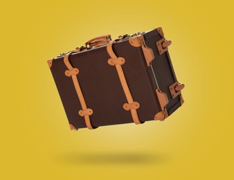 Image of Vintage suitcase in air on yellow background