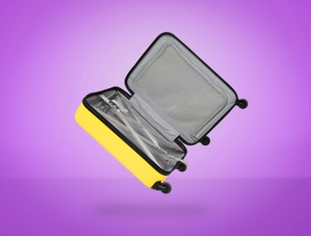 Image of Open empty suitcase in air on violet background