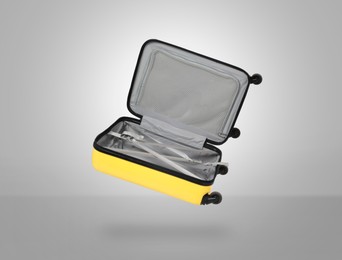 Image of Open empty suitcase in air on light grey background