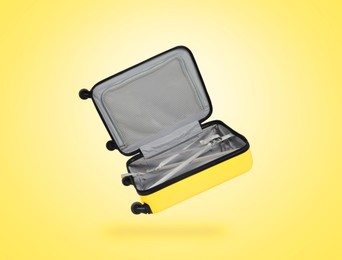 Image of Open empty suitcase in air on light yellow background