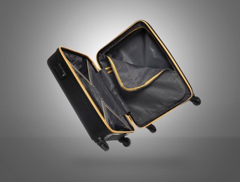 Image of Open empty suitcase in air on grey background