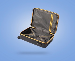 Image of Open empty suitcase in air on light blue background