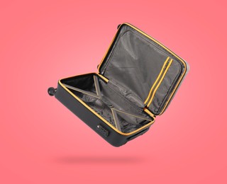 Image of Open empty suitcase in air on coral background