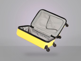 Image of Open empty suitcase in air on light grey background