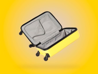 Image of Open empty suitcase in air on yellow background