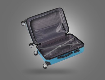 Image of Open empty suitcase in air on grey background