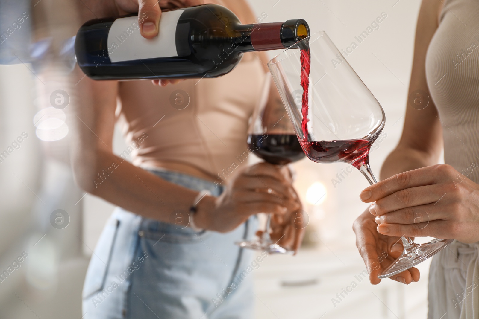 Photo of Man pouring red wine into woman`s glass indoors, selective focus