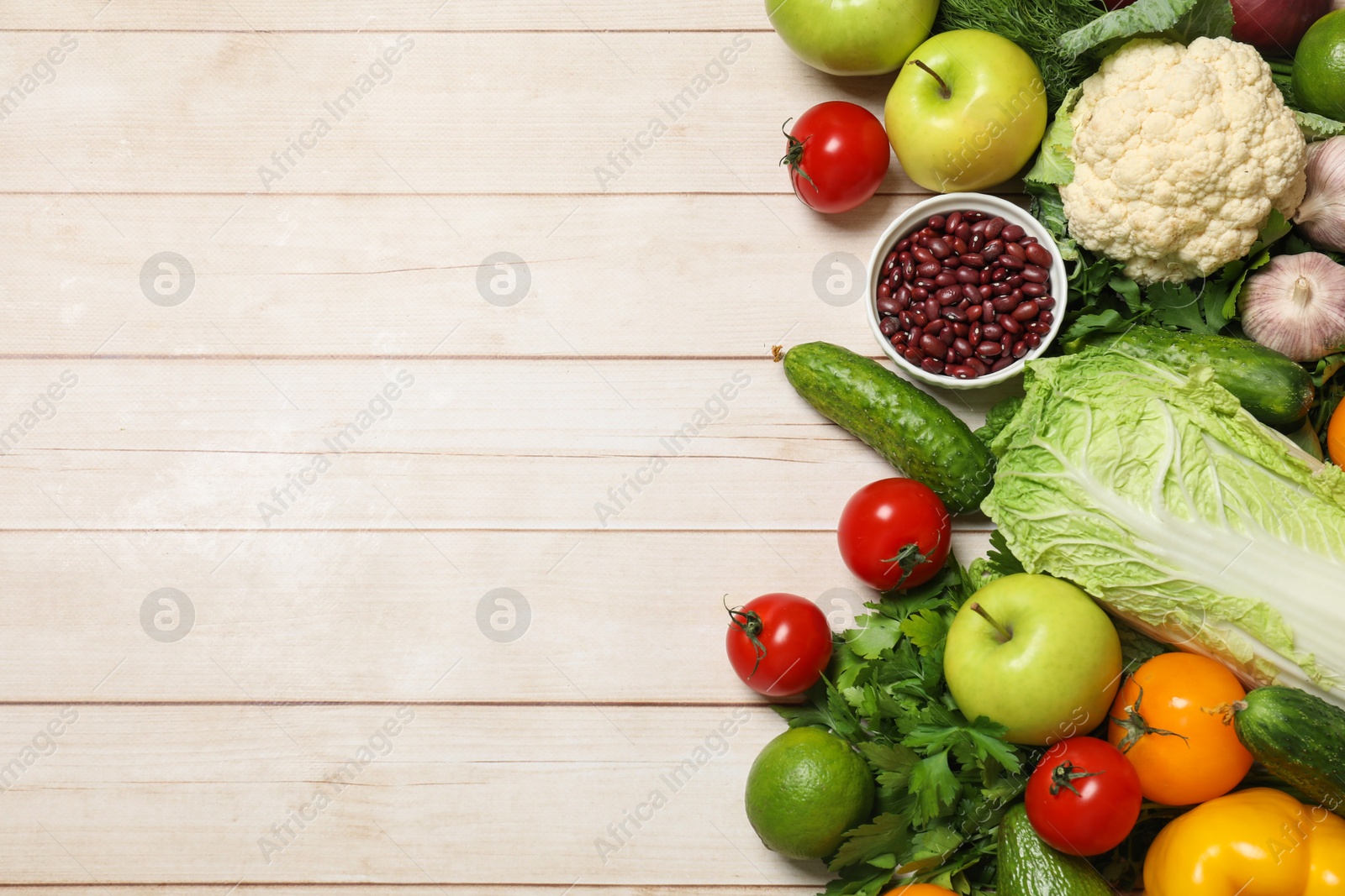 Photo of Different vegetarian products on light wooden table, top view. Space for text