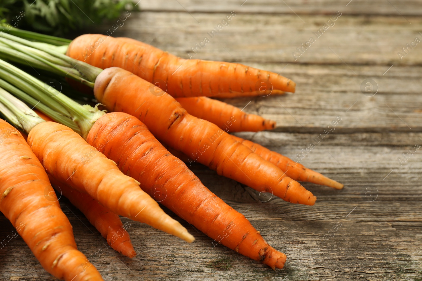 Photo of Tasty ripe juicy carrots on wooden table, closeup