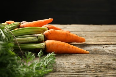 Photo of Tasty ripe juicy carrots on wooden table, closeup. Space for text