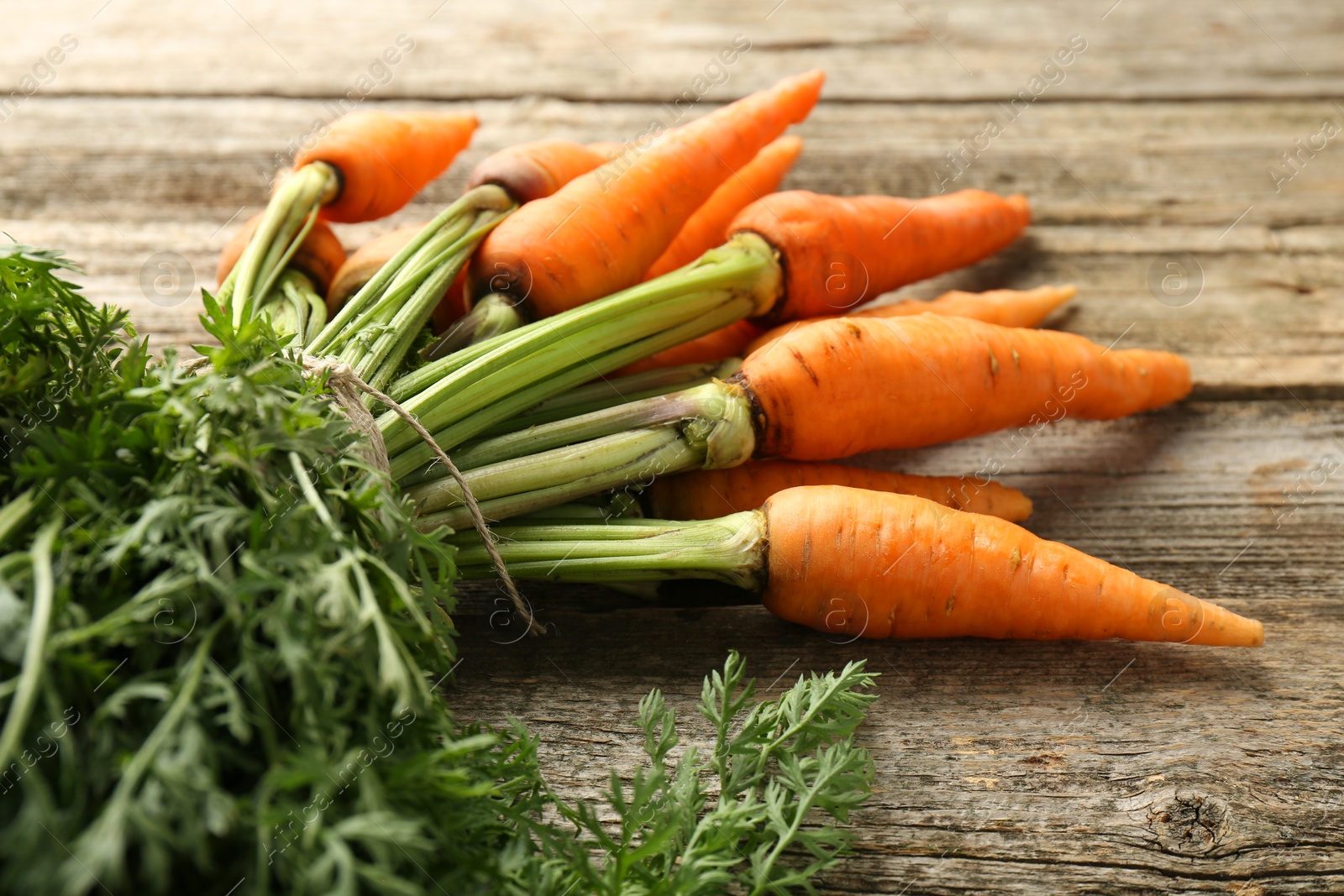 Photo of Tasty ripe juicy carrots on wooden table, closeup