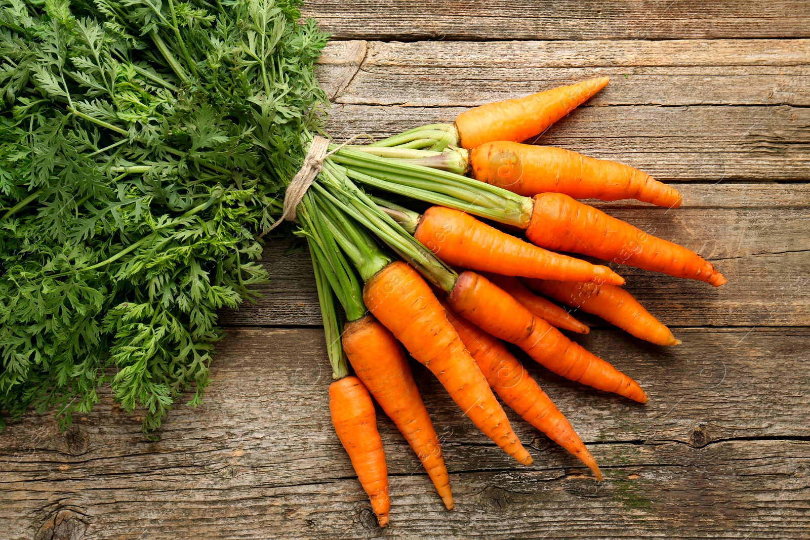 Photo of Bunch of tasty ripe juicy carrots on wooden table, top view