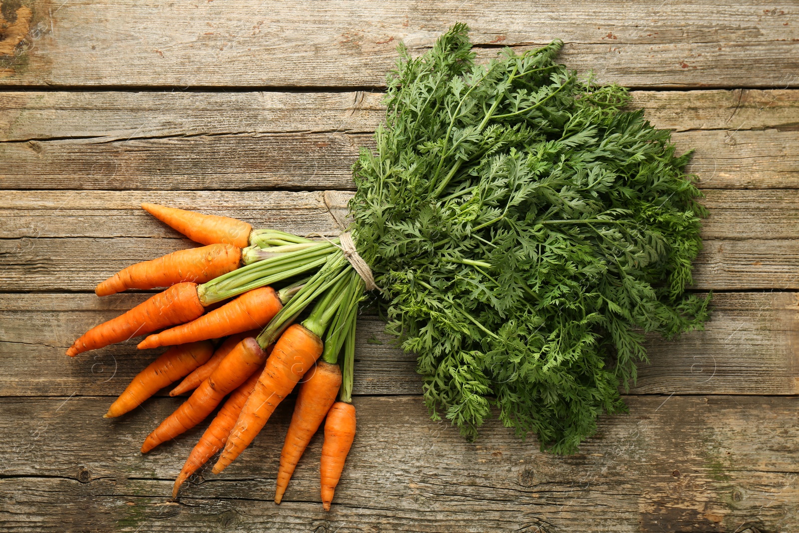 Photo of Bunch of tasty ripe juicy carrots on wooden table, top view