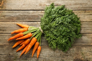 Photo of Bunch of tasty ripe juicy carrots on wooden table, top view