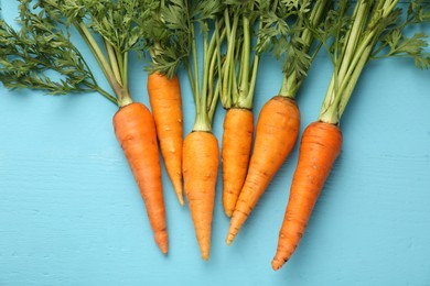 Tasty ripe juicy carrots on light blue wooden table, flat lay