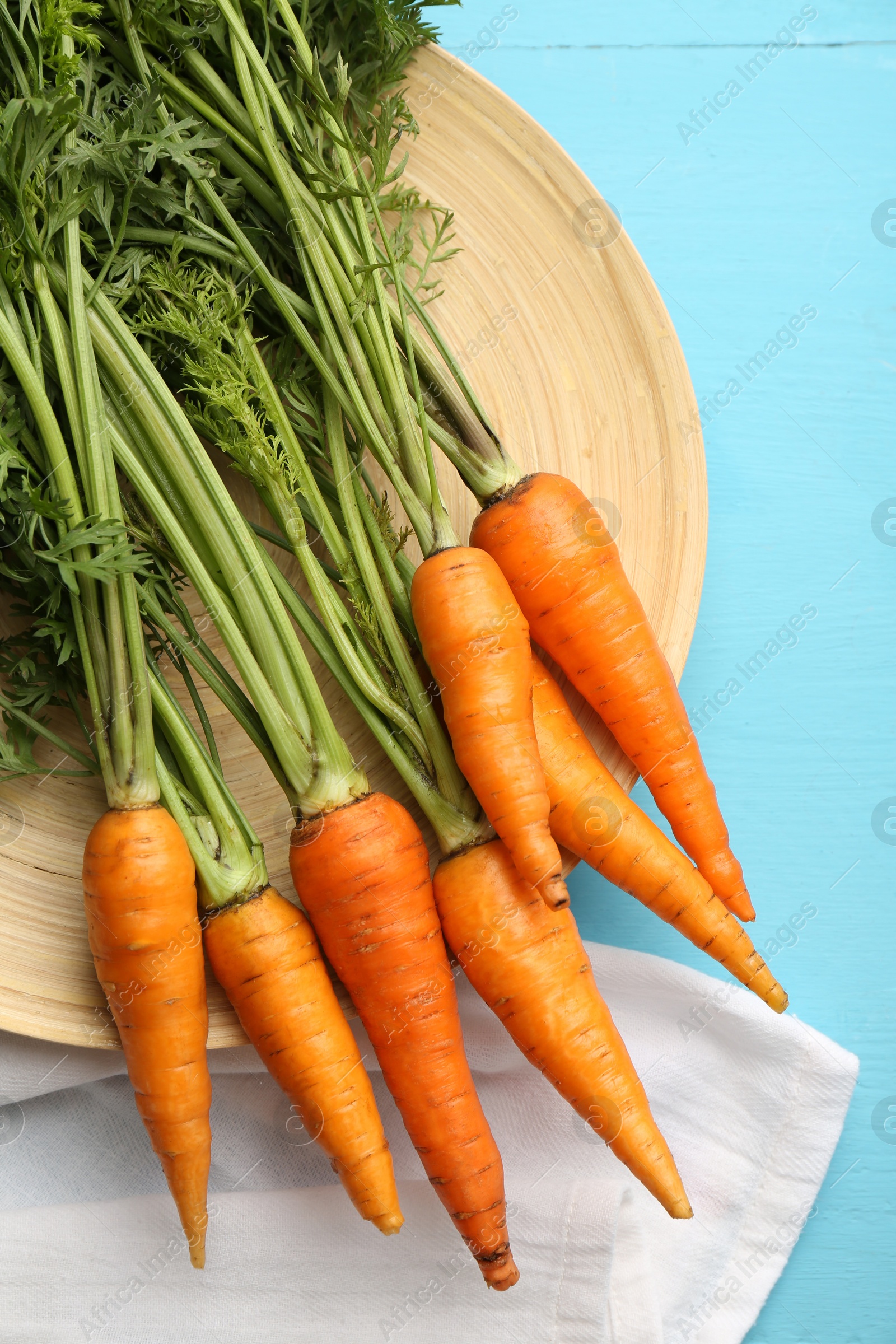 Photo of Tasty ripe juicy carrots on light blue wooden table, flat lay