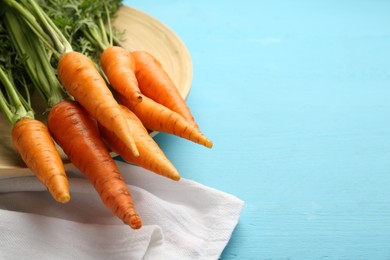 Photo of Tasty ripe juicy carrots on light blue wooden table, space for text