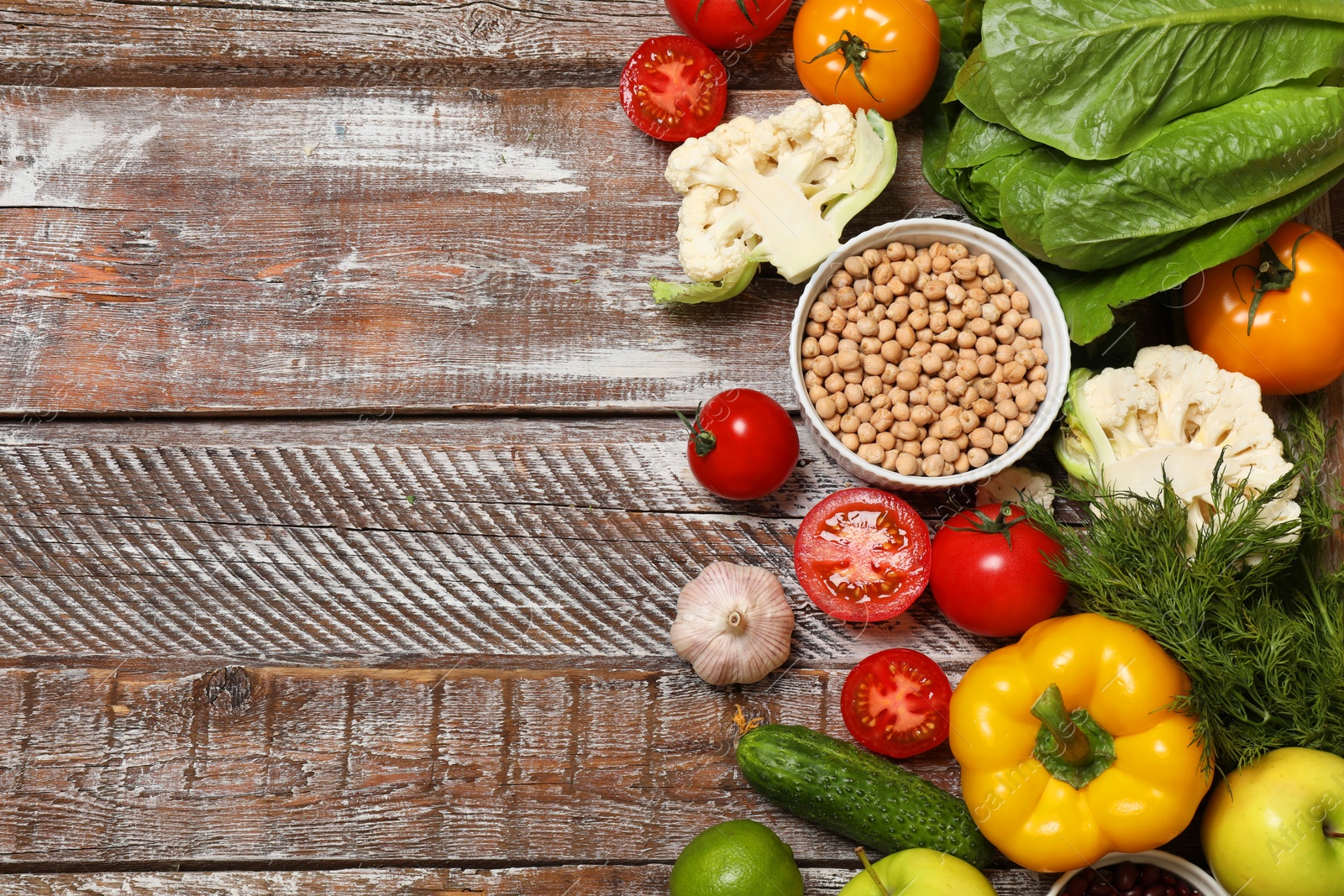 Photo of Different vegetarian products on wooden table, top view. Space for text