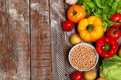 Photo of Different vegetarian products on wooden table, top view. Space for text