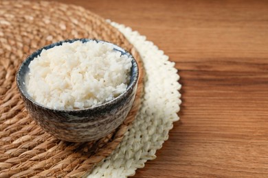 Tasty cooked rice in bowl on wooden table, space for text