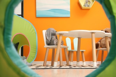 Photo of Stylish child room interior with different toys and furniture, view from play tent