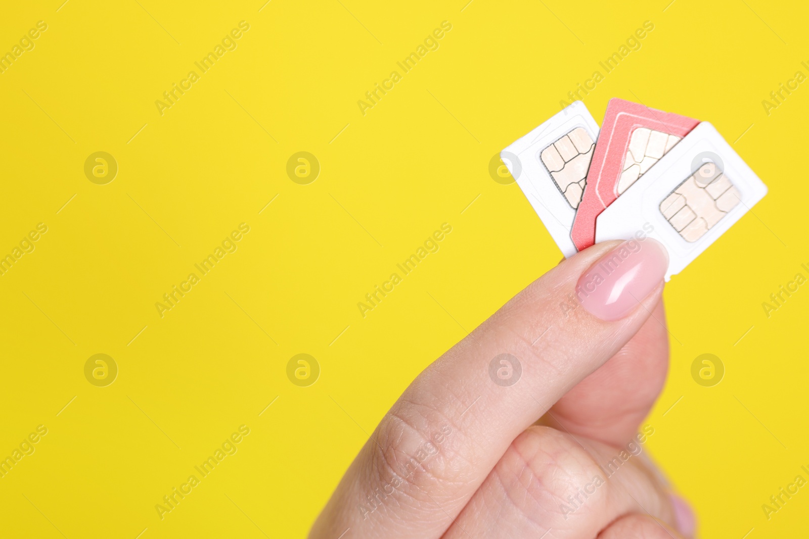 Photo of Woman holding SIM cards on yellow background, closeup. Space for text