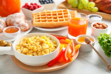 Photo of Tasty breakfast. Scrambled eggs in bowl, bell pepper and other food on light table, closeup