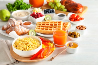 Photo of Tasty breakfast. Scrambled eggs in bowl, cut bell pepper, honey and other food on light table