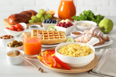 Photo of Tasty breakfast. Scrambled eggs in bowl, cut bell pepper, honey and other food on light table