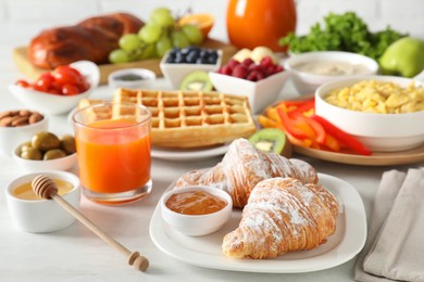 Photo of Tasty breakfast. Croissants, jam, honey and other food on light table