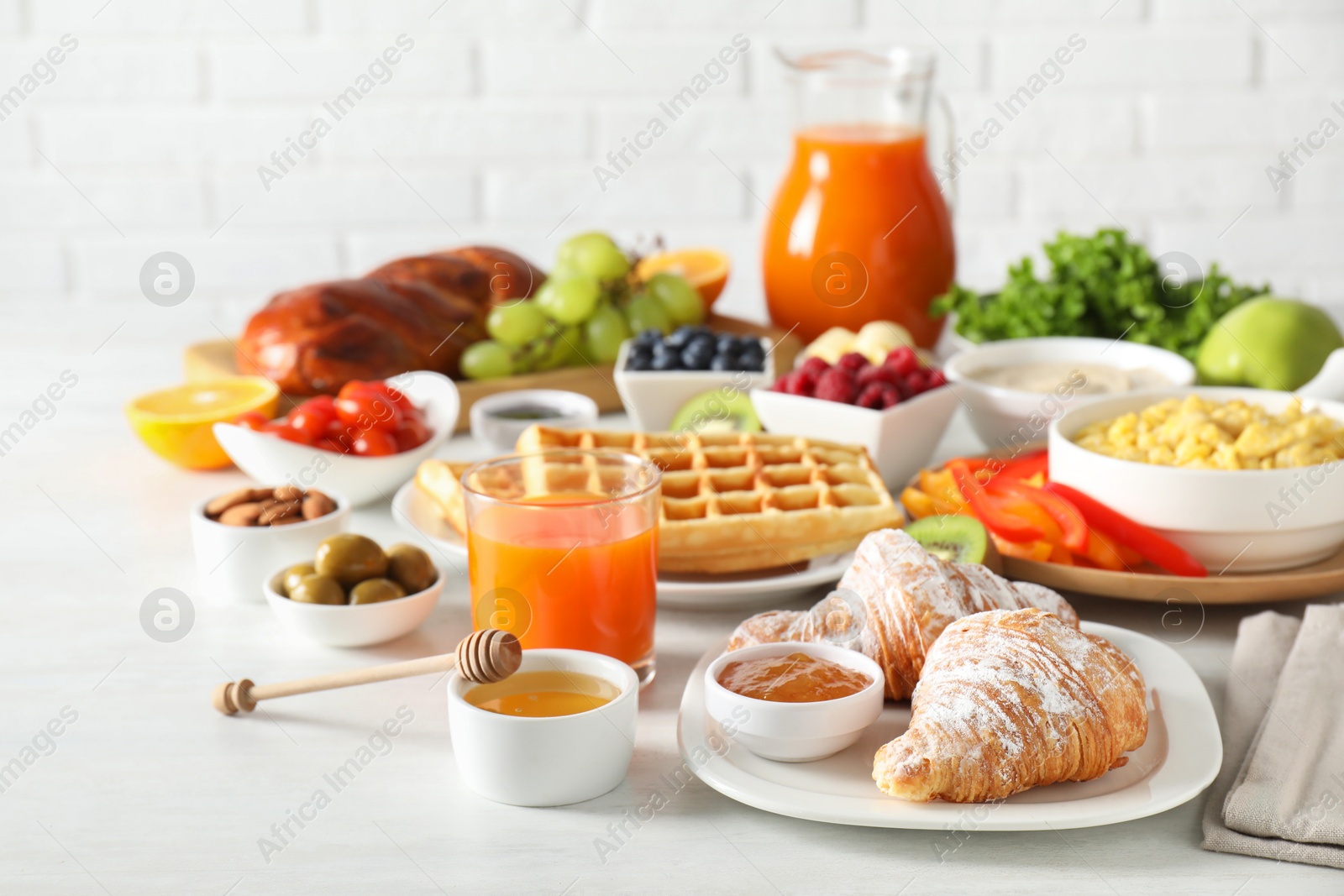 Photo of Tasty breakfast. Croissants, jam, honey and other food on light table