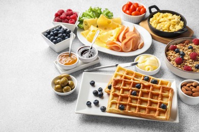 Tasty breakfast. Belgian waffles, blueberries and other food on grey textured table