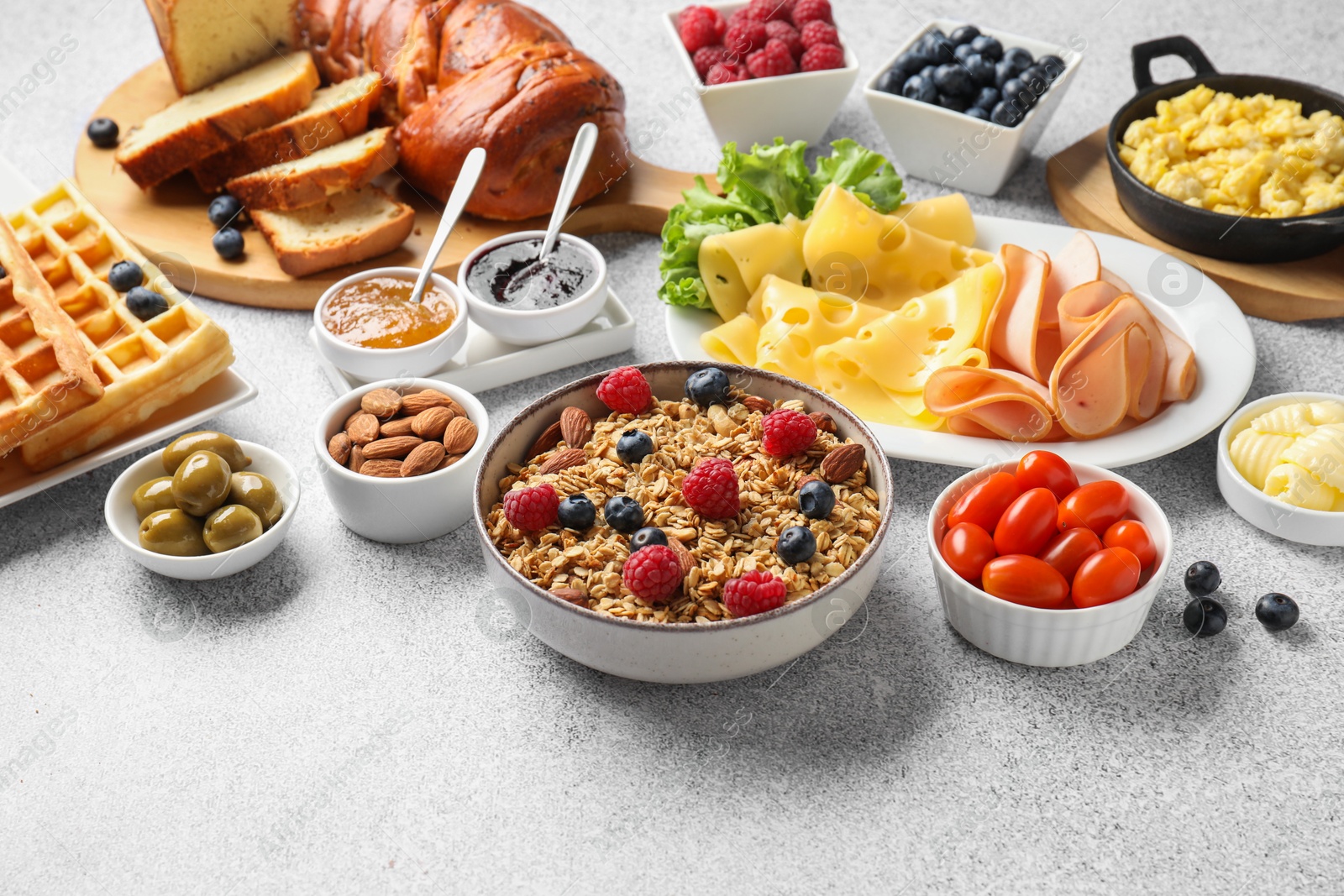 Photo of Tasty breakfast. Granola with berries and other food on grey textured table