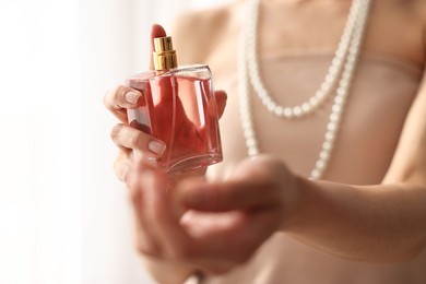 Photo of Woman with bottle of perfume on blurred background, closeup