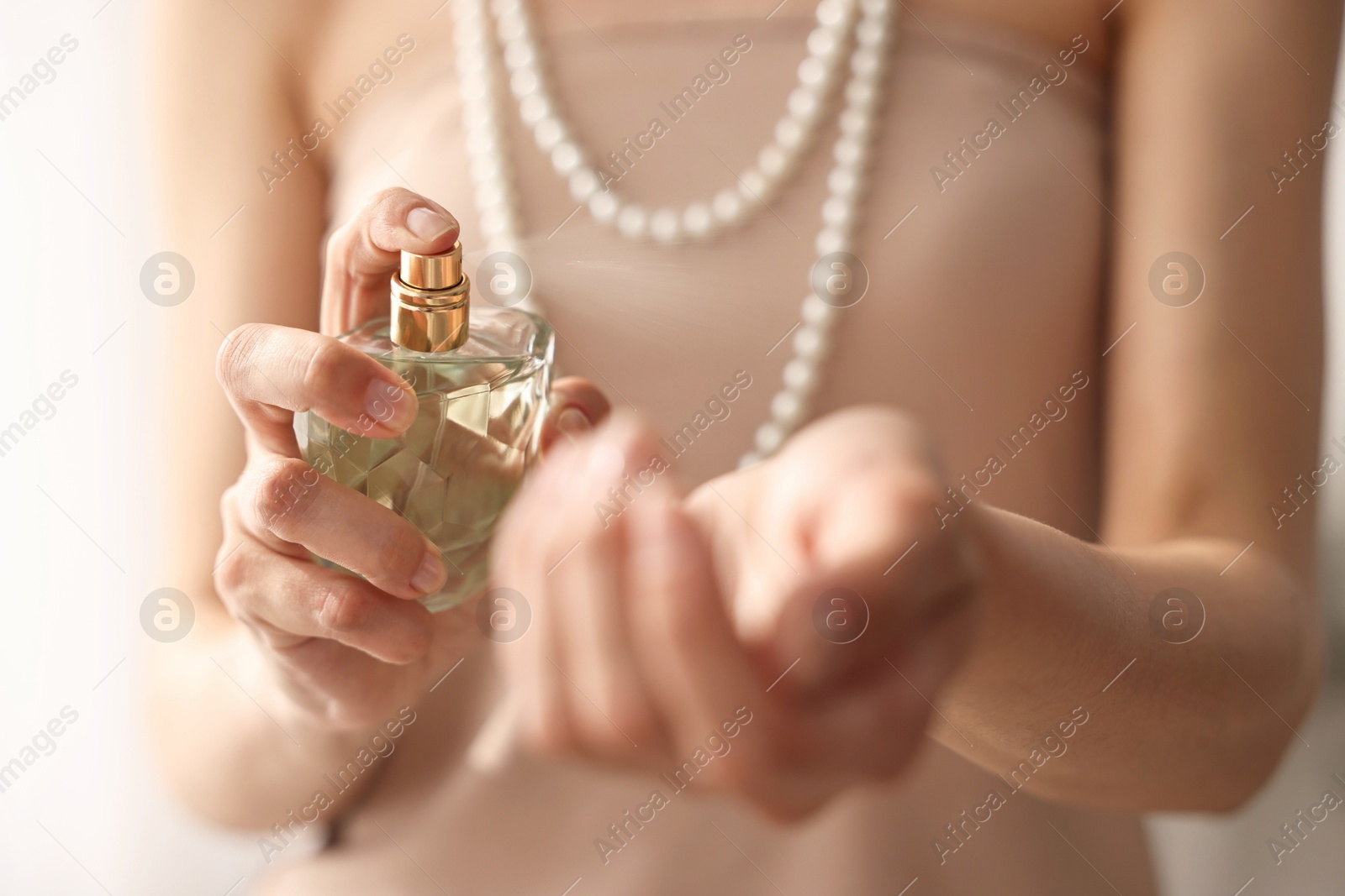 Photo of Woman spraying perfume onto wrist indoors, closeup