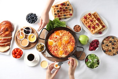 People having breakfast at white table, top view