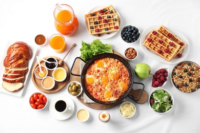 Different meals served for breakfast on white table, flat lay