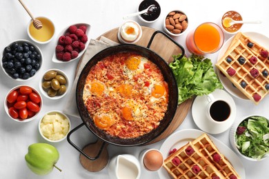 Different meals served for breakfast on white table, flat lay