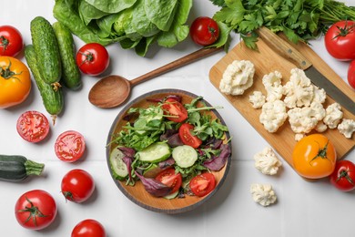 Photo of Healthy vegetarian food. Salad in bowl and vegetables on white tiled table, flat lay