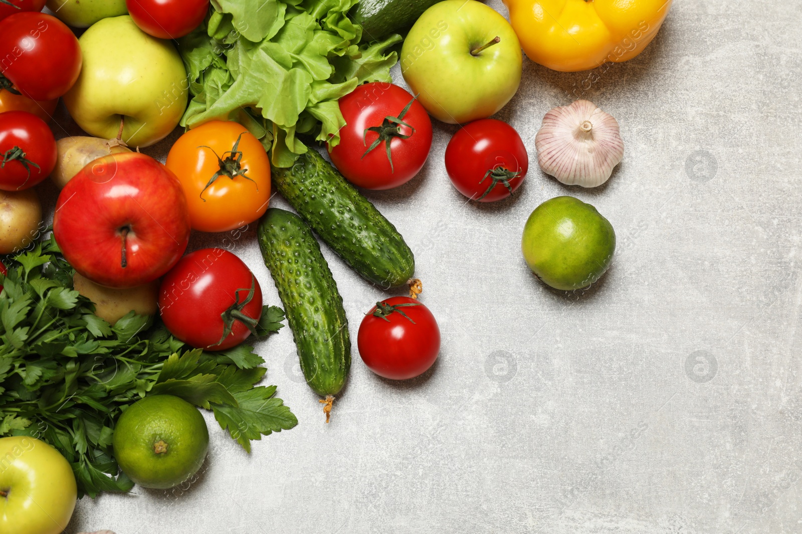 Photo of Healthy vegetarian food. Different vegetables and apples on grey textured table, flat lay. Space for text