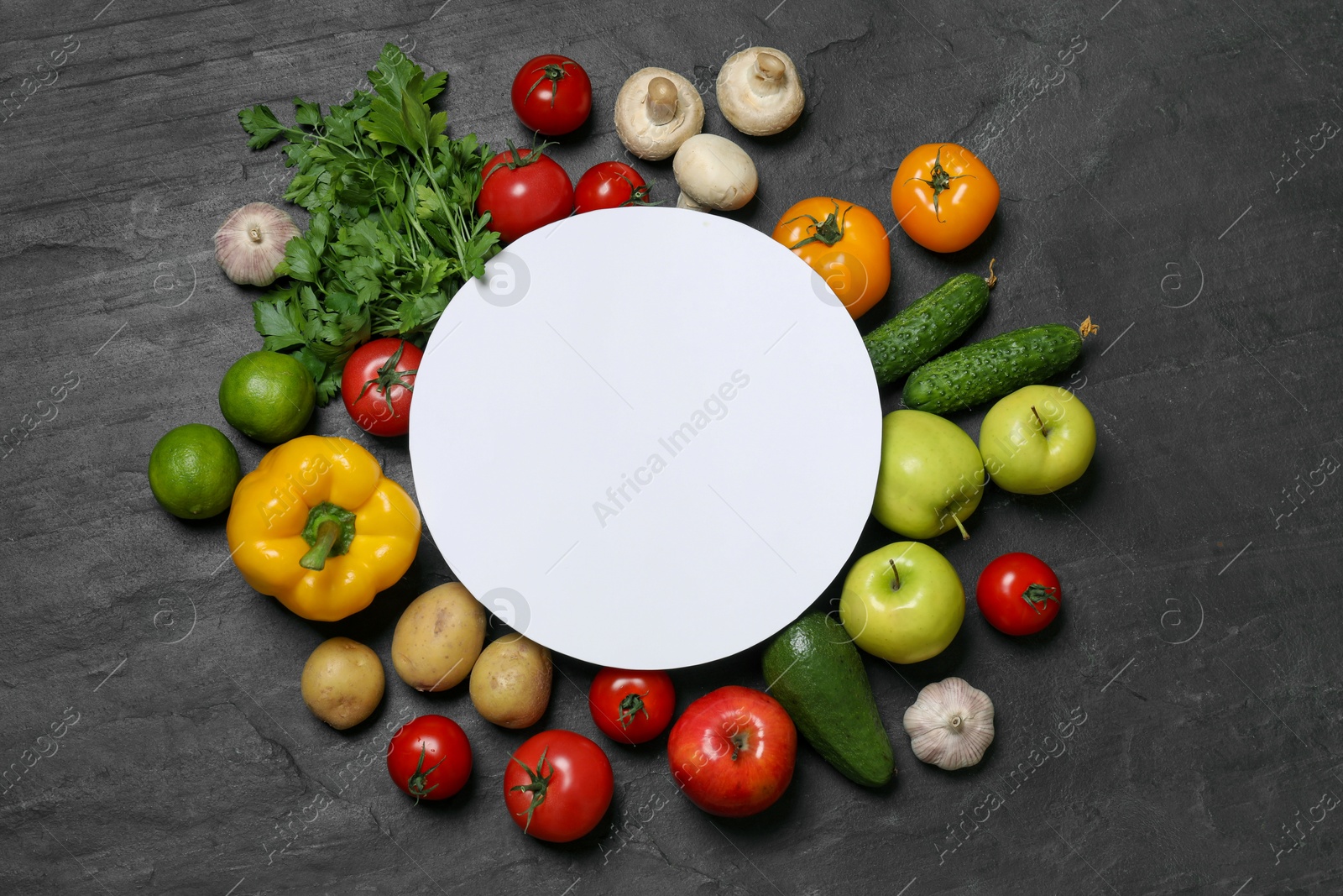 Photo of Healthy vegetarian food. Paper card surrounded by different vegetables, mushrooms and fruits on dark textured table, flat lay