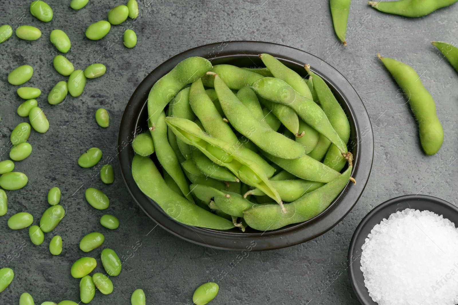 Photo of Raw green edamame soybeans and pods on grey table, flat lay